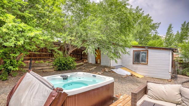 Ein Garten mit Whirlpool, Holzterrasse und einem kleinen Gartenhaus.