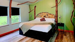 A bedroom with a bed, a window, and a wall with tree branch decorations.