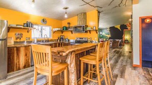 A kitchen with wooden bar stools, a refrigerator, and a microwave.