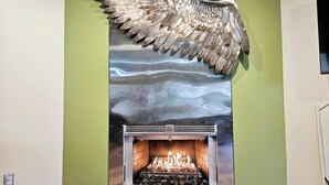 A fireplace with a metallic wing sculpture above it.