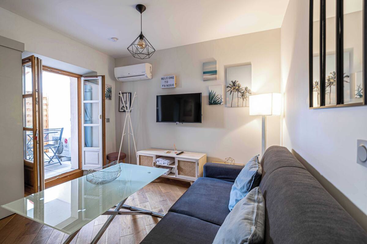 A modern living room with a glass table, grey sofa, and a TV.