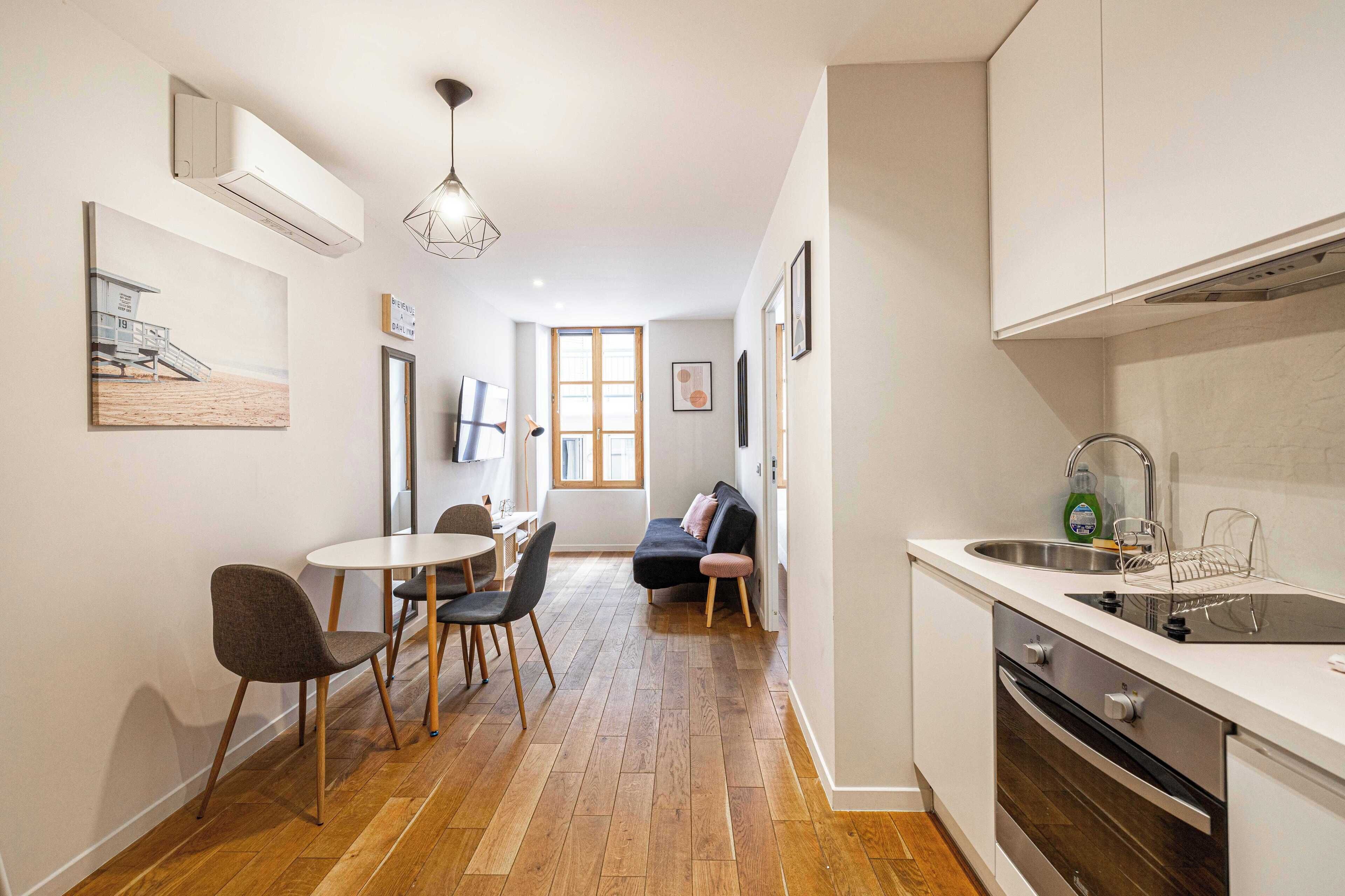 Une cuisine compacte comprenant un évier, une cuisinière et un coin repas avec des chaises et une table.