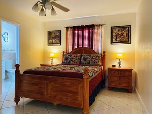 A bedroom with a wooden bed, two bedside tables with lamps, a ceiling fan, and two framed pictures on the wall. - ANDY RESORT in charming Cutler Bay with AC, WiFi  . Bbq and more (Cutler Bay)