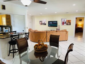 A modern living room with a glass dining table, leather sofa, and a TV mounted on the wall. - ANDY RESORT in charming Cutler Bay with AC, WiFi  . Bbq and more (Cutler Bay)