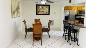 A compact kitchen with a dining area, featuring a ceiling fan, a refrigerator, a microwave, and a sink.