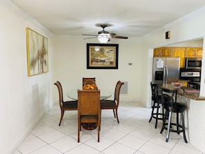 A compact kitchen with a dining area, featuring a ceiling fan, a refrigerator, a microwave, and a sink.