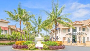 A hotel with a central fountain, palm trees, and a well-maintained garden.