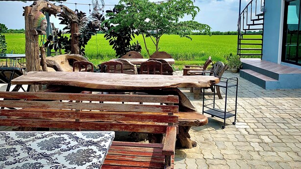 Un espace extérieur aménagé avec des meubles en bois rustique, une nappe à motifs et une vue sur un champ verdoyant.