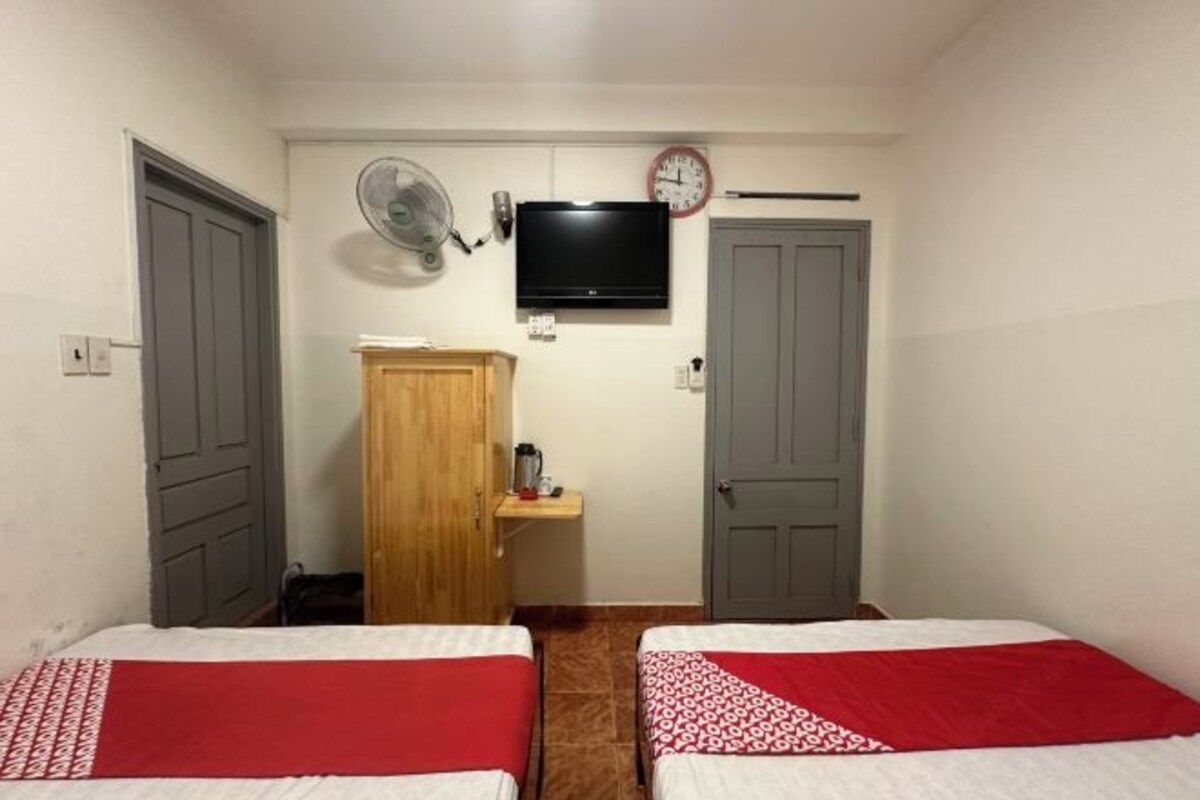 Een ruime, schone kamer met twee bedden, een televisie, een wekker en een ventilator.