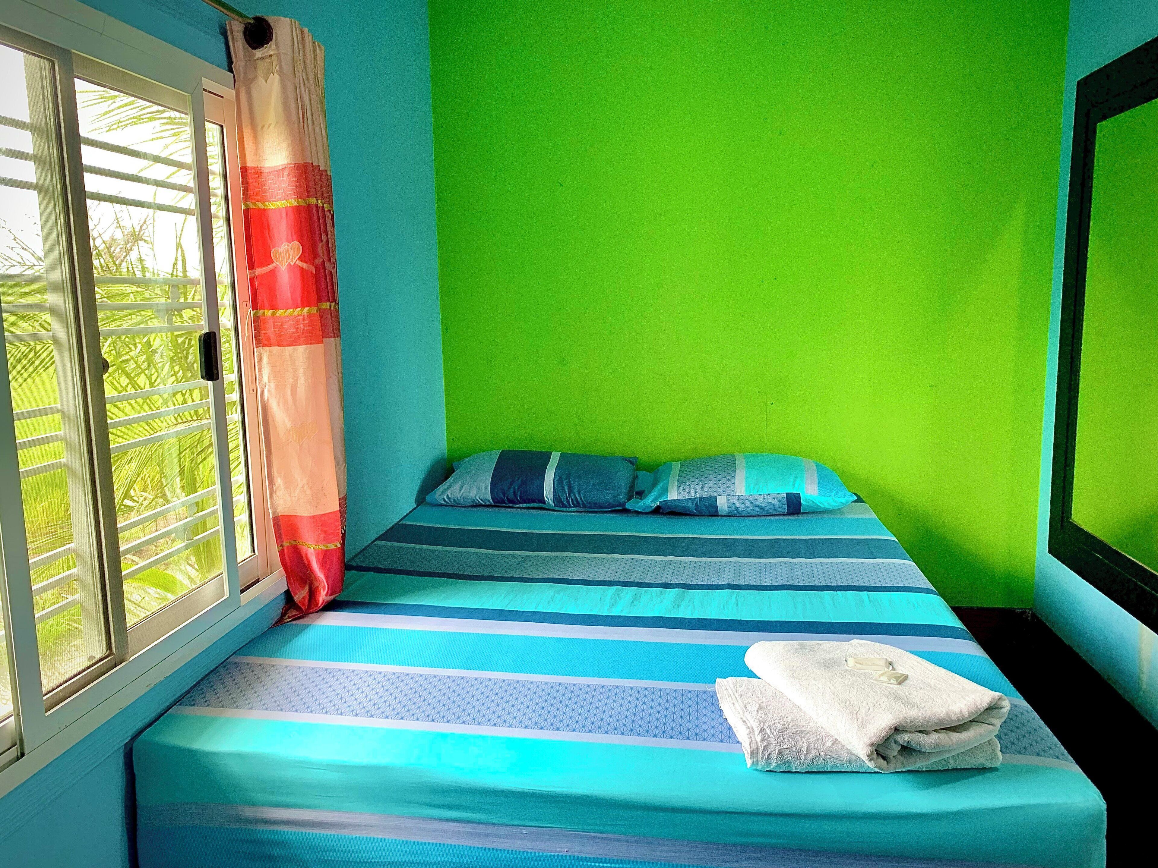 A room with a bed, a window with curtains, and a green wall.
