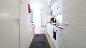 Een moderne keuken met witte kastjes, een magnetron en een koffiezetapparaat.