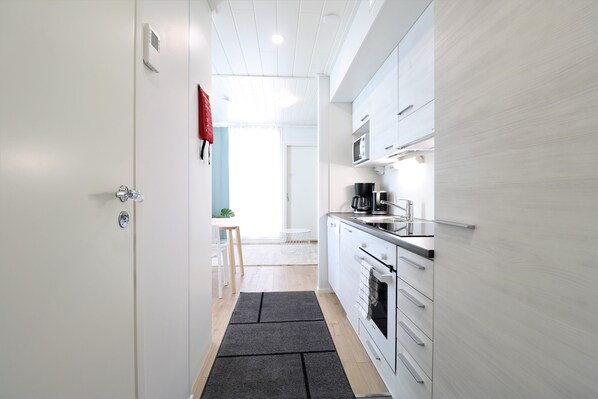 A modern kitchen with white cabinets, a microwave, and a coffee maker.