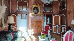 A room with a chandelier, ornate furniture, and a large portrait on the wall. - A journey through time in the heart of the city (Chalon-sur-Saône)