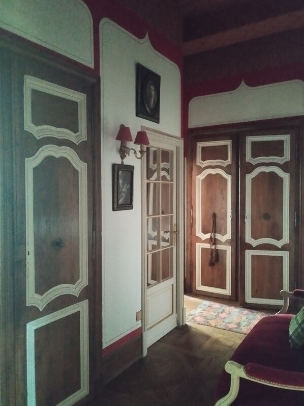 Una habitación con puertas de madera, una pared blanca con un cuadro enmarcado y un sofá rojo.