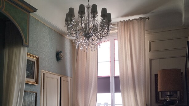 A traditional room with a bed, a chandelier, a desk, and a chair. - A journey through time in the heart of the city (Chalon-sur-Saône)