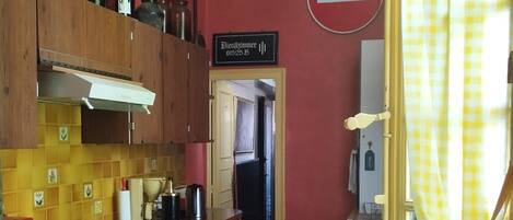 Una cocina con armarios de madera, una mesa verde y un suelo de cuadros.