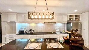 Cocina moderna con armarios blancos, encimera negra y comedor para cuatro.