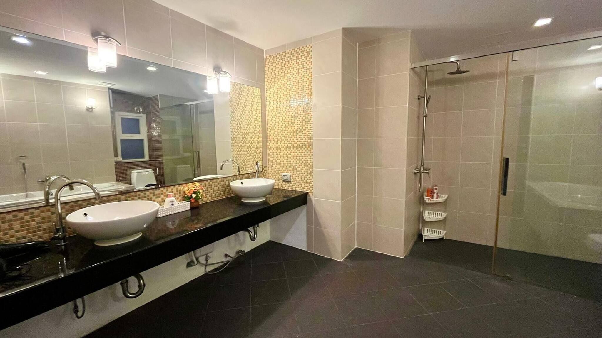 Une salle de bain moderne avec deux lavabos, un grand miroir et une douche à parois de verre.
