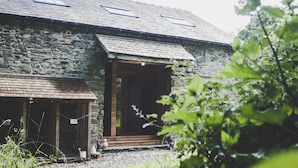 A stone building with a wooden porch and a small entrance. - THE HAYLOFT at Sunny Brow Farm in the heart of the Lake District National Park.  (Ambleside)