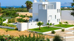 A modern white building with solar panels, a pool, and a view of the sea and mountains. - Lilu Villa 2 With Private Pool and Seaview (Kos)