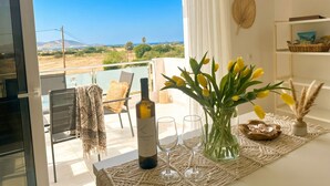 A balcony with a view of the countryside, a bottle of wine, glasses, and a vase with yellow flowers. - Lilu Villa 2 With Private Pool and Seaview (Kos)