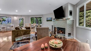Una sala de estar moderna con chimenea, asientos cómodos y ventanas amplias.