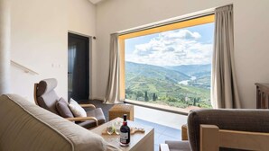 A modern living room with a large window offering a scenic view of a valley and mountains.