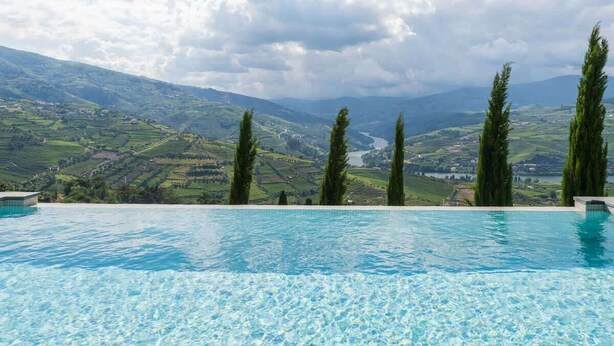 A pool with a view of rolling hills and a river.