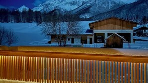 A snow-covered mountain landscape at night with a wooden building in the foreground. - Haus Sabine (Leutasch)