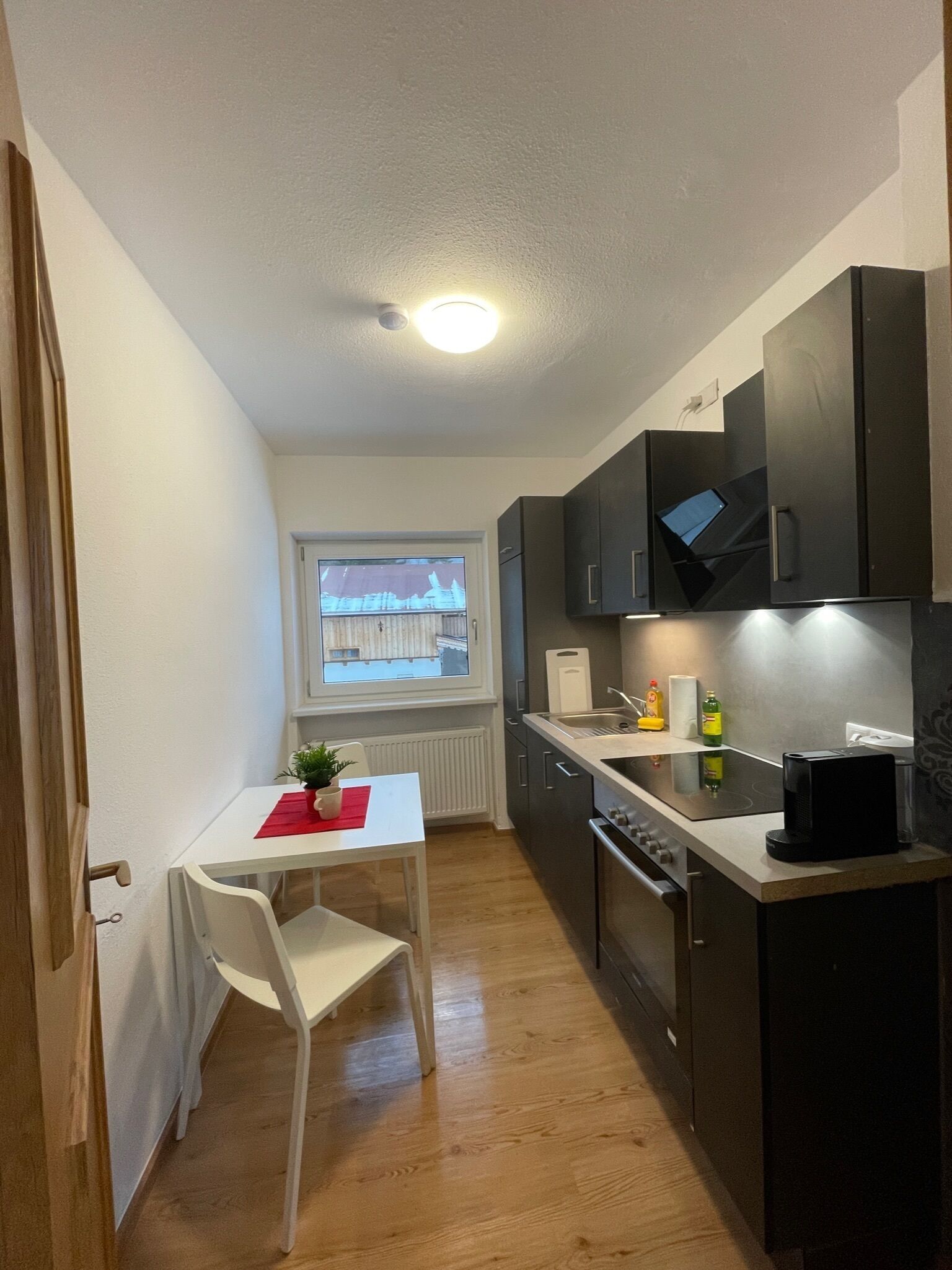 A compact kitchen with a dining area, a window with a view, and modern appliances.