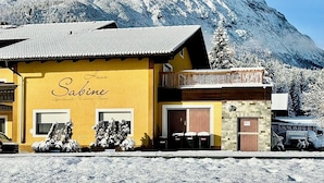 A yellow building with the name "Sabine" on the facade, a balcony, and a mountain in the background. - Haus Sabine (Leutasch)