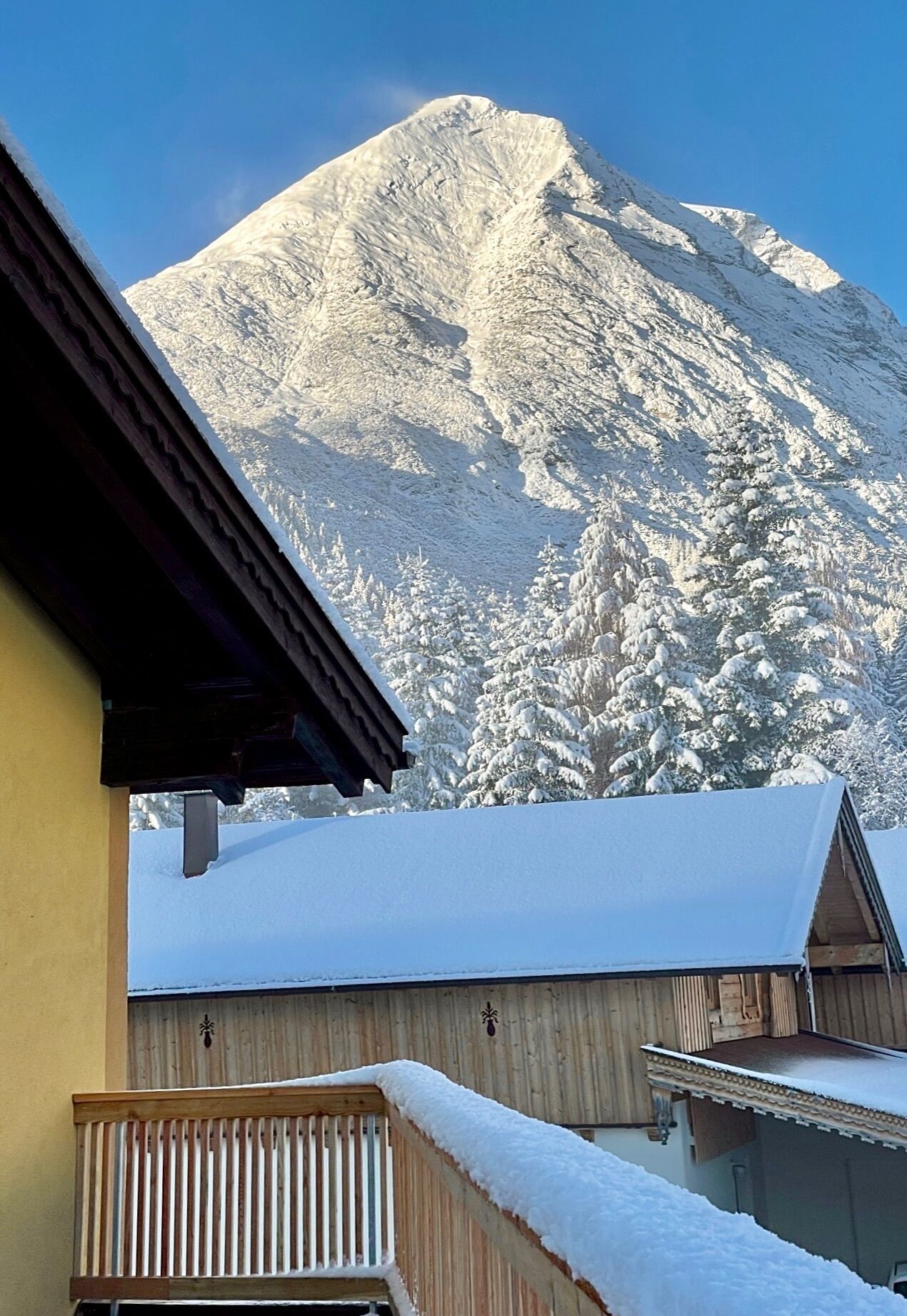 Una montaña con laderas nevadas y un edificio de fachada de madera al frente.