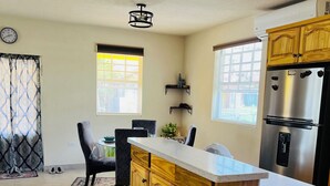 A kitchen with a wooden island, a built-in refrigerator, and a dining area with chairs and a table. - GAIA Barbados! 2 BD Home 5min walk to the beach (Bridgetown)
