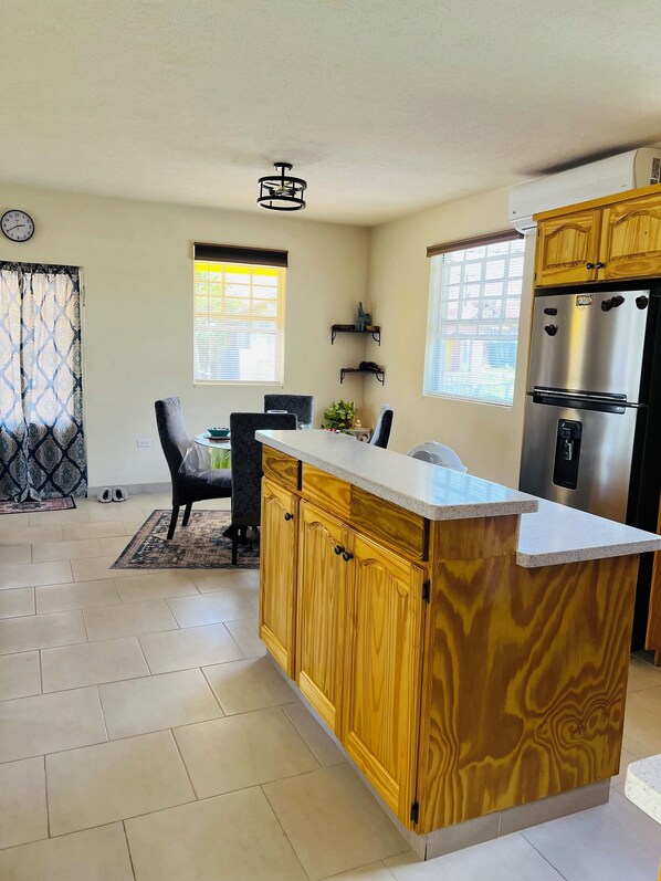 A kitchen with a wooden island, a built-in refrigerator, and a dining area with chairs and a table.
