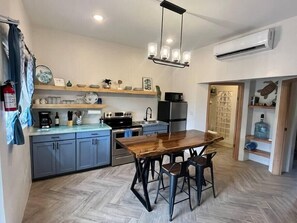 A compact kitchen with a wooden dining table, grey cabinets, and a built-in oven.