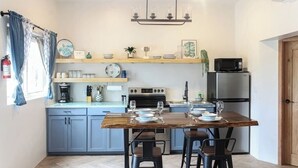 A modern kitchen with grey cabinets, a wooden dining table, and a built-in oven. - Seashell Suite, Garden & Pool Views @SapphireBeach (San Pedro Town)