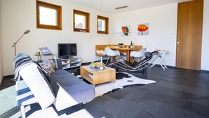 Ein modernes Wohnzimmer mit einer Couch, einem Fernseher, einem Esstisch und Stühlen.