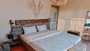 Ein gemütliches Schlafzimmer mit einem hölzernen Bett, einer gewobenen Bank und einem gemusterten Teppich.