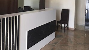 Een receptiebalie met een modern ontwerp, inclusief een marmeren paneel, een spiegel en een wandairconditioner.
