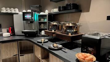 A modern kitchen with a coffee machine, a food warmer, and a basket of eggs.
