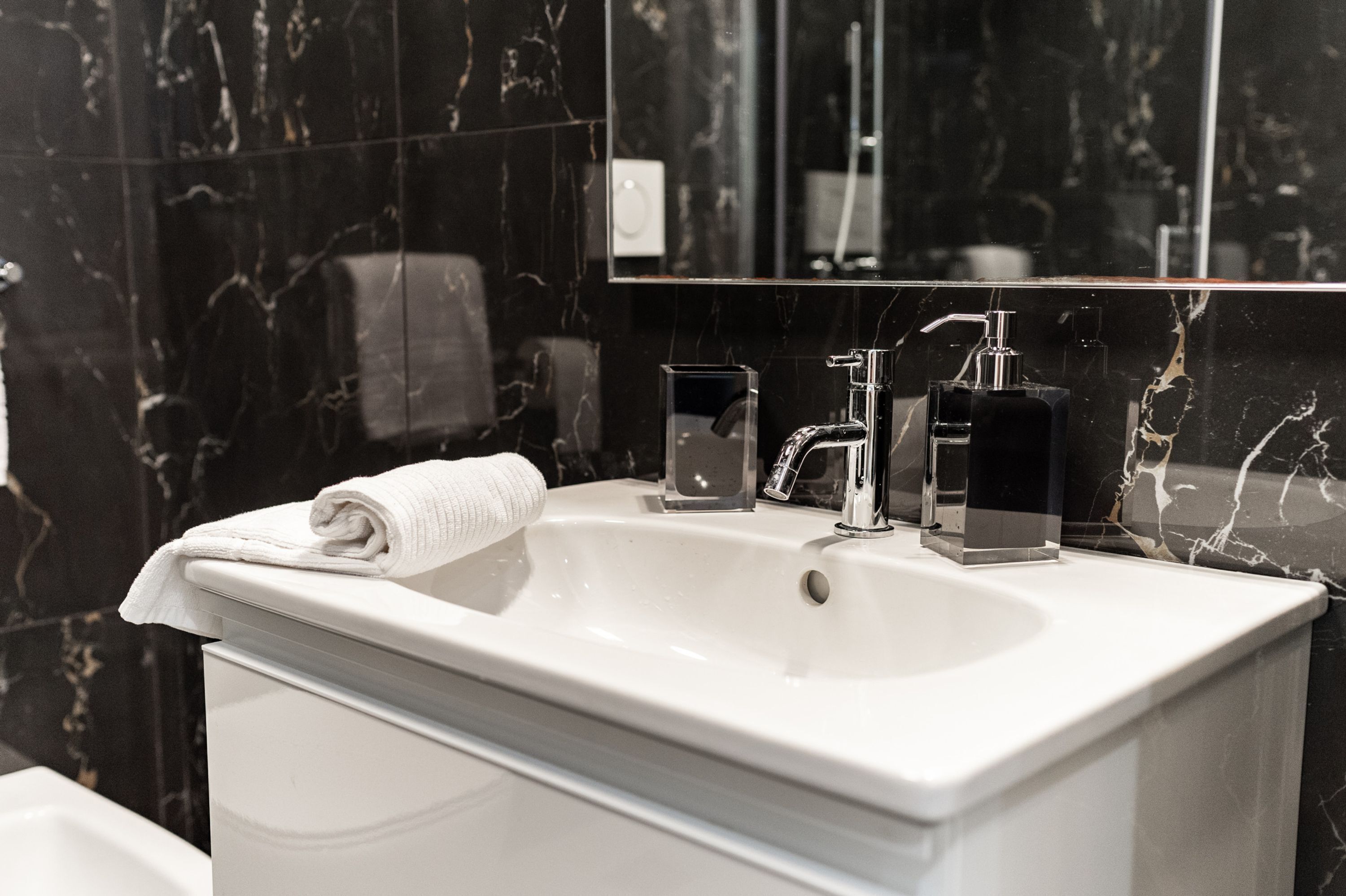 A bathroom with a white sink, a mirror, and a towel.