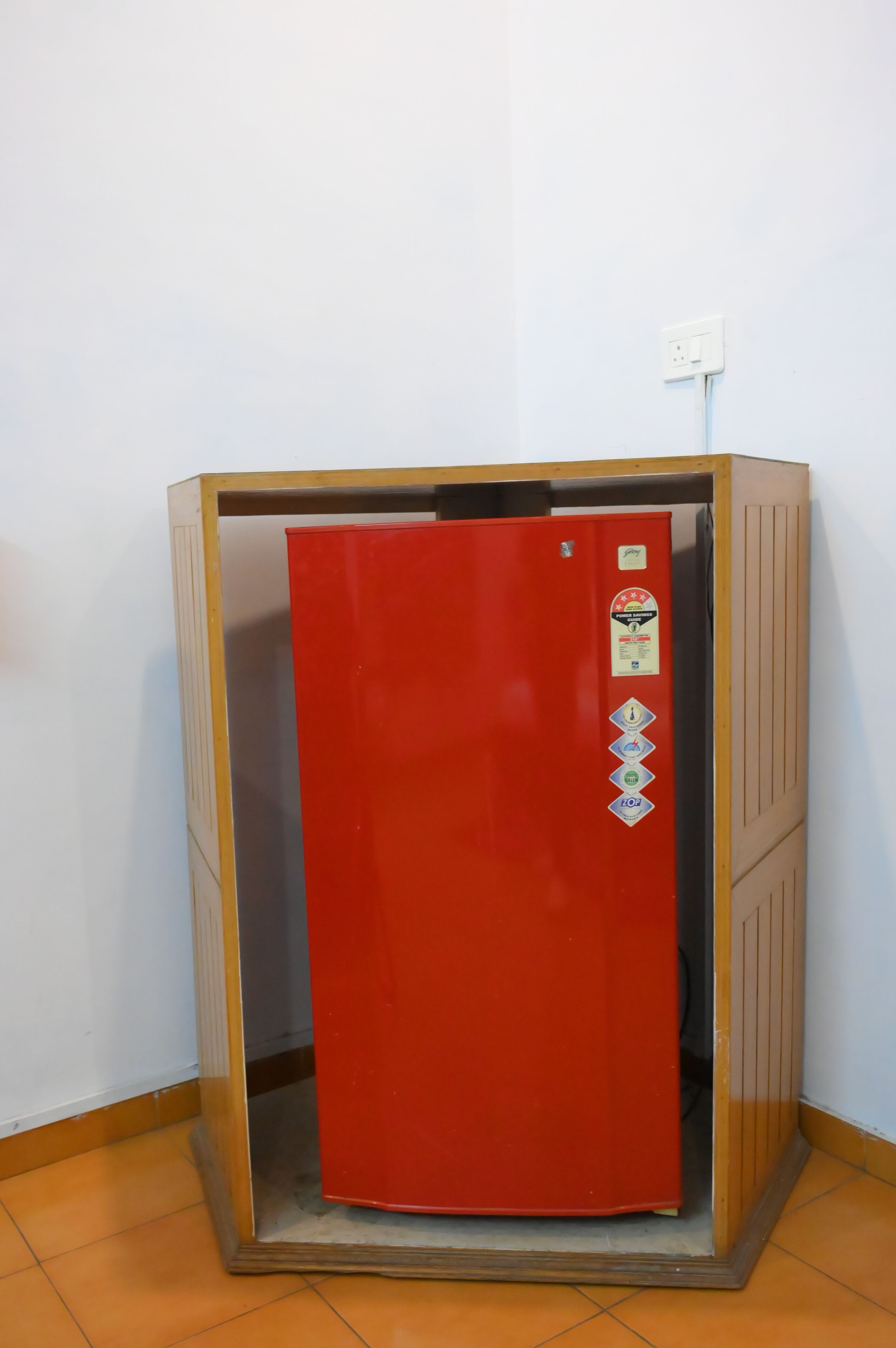 Ein roter Aufzug mit Holzrahmen, eine wandmontierte Steckdose und ein gefliester Boden.