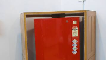 Ein roter Aufzug mit Holzrahmen, eine wandmontierte Steckdose und ein gefliester Boden.