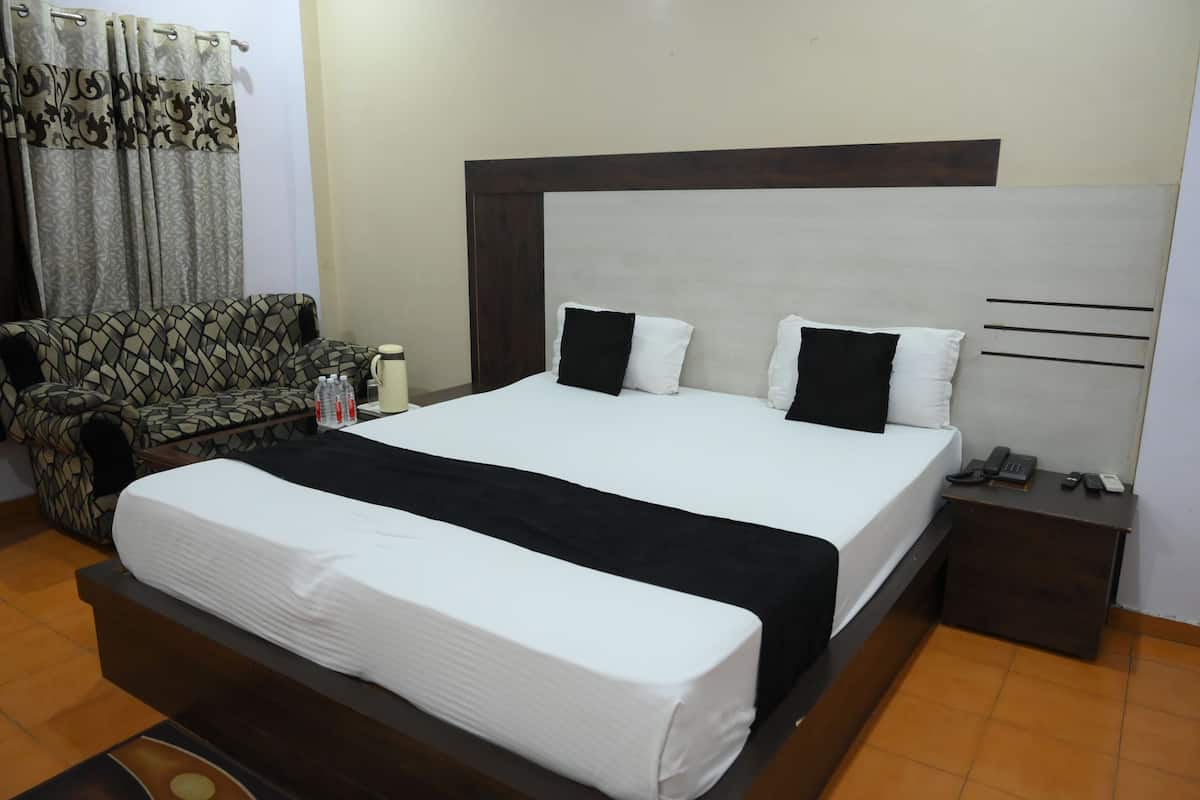 A hotel room with a bed, bedside table, and a sofa.