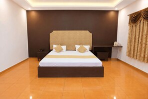Une chambre d’hôtel avec un grand lit, une table de chevet, une commode et une étagère fixée au mur.