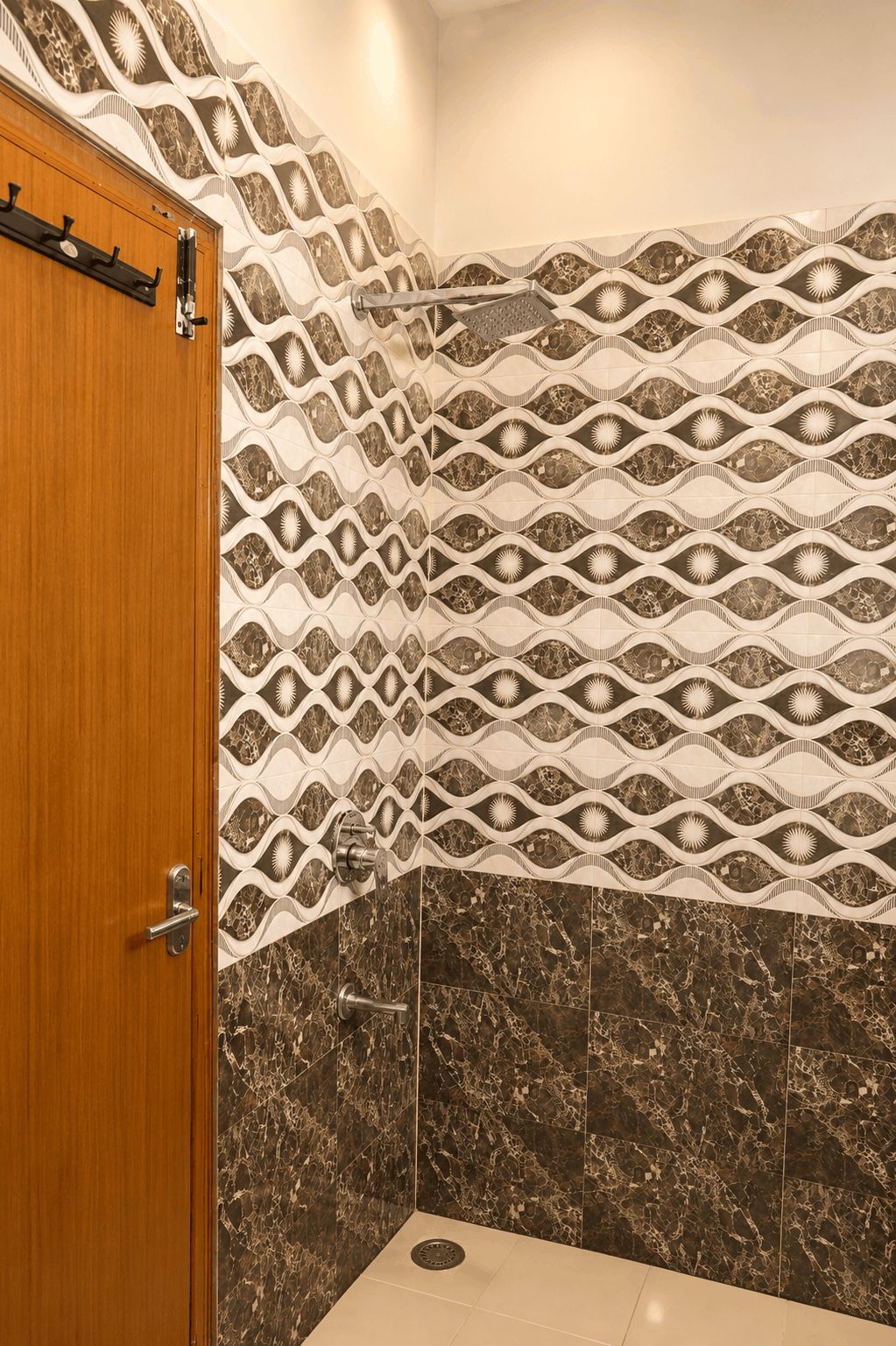 Une salle de bain avec une porte en bois, des carreaux muraux à motifs et un sol en marbre.