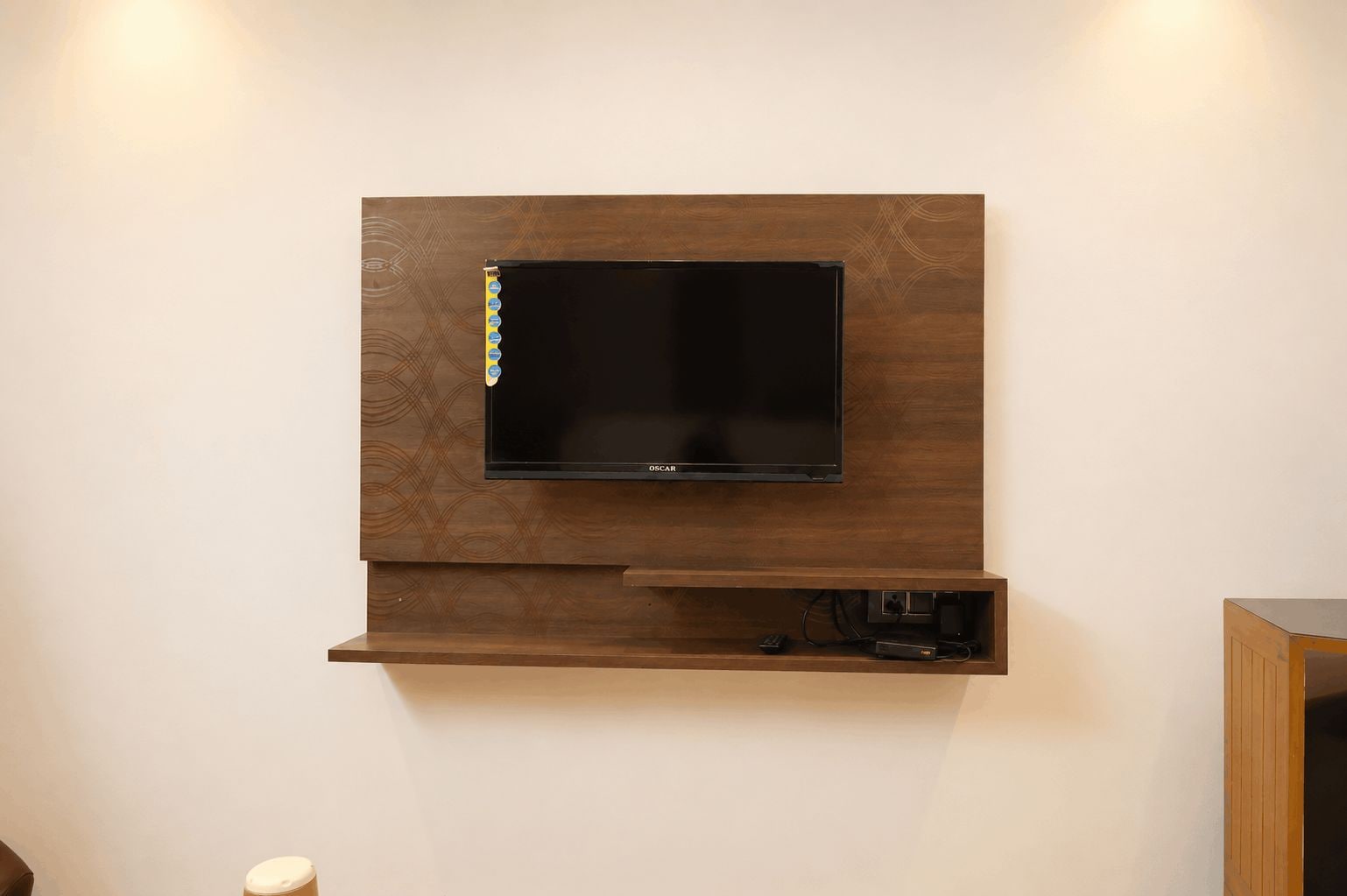 Un televisor de pantalla plana montado en una pared de madera, con un estante debajo.