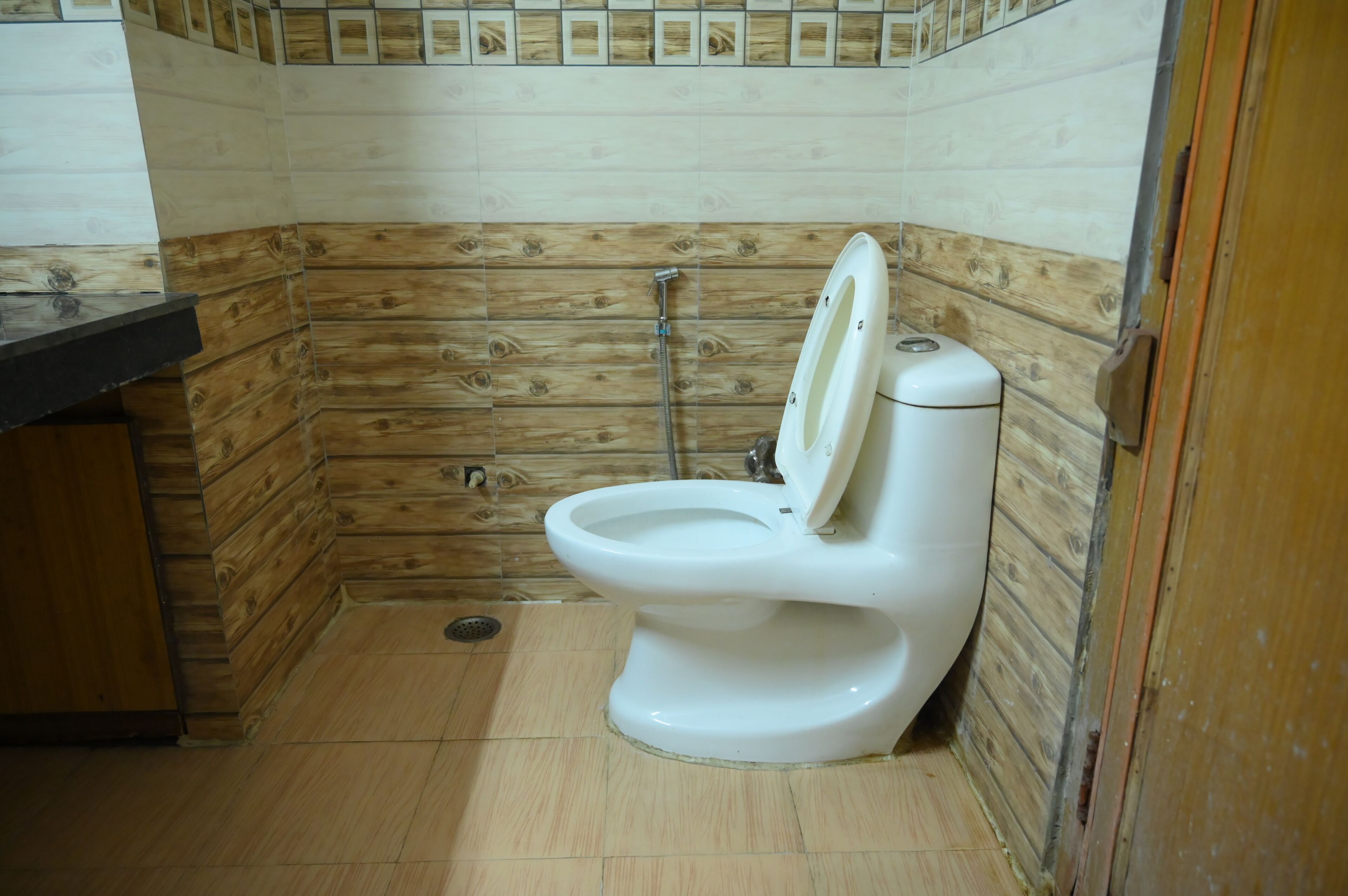 A bathroom with a wooden wall panel design, a white toilet, and a shower area.