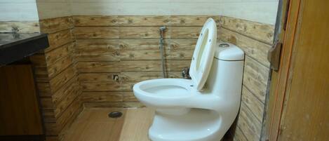 A bathroom with a wooden wall panel design, a white toilet, and a shower area.