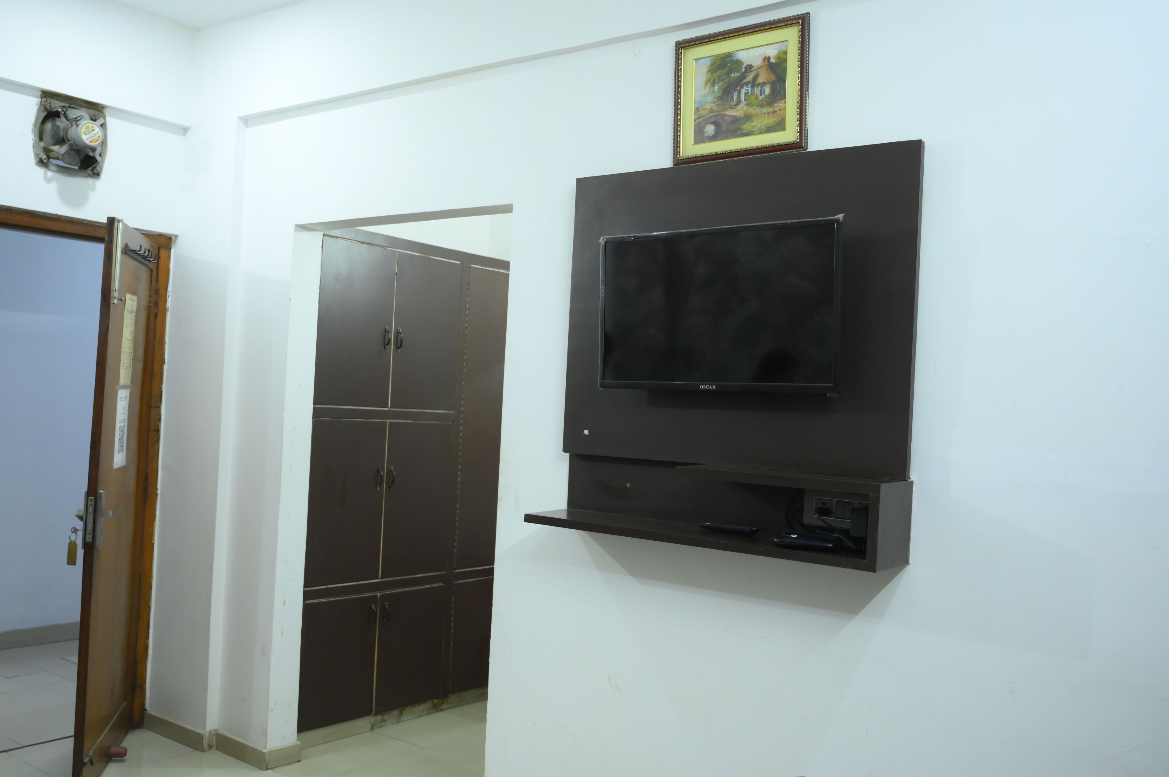 Habitación con televisor de pantalla plana montado, puerta con cerradura y armario con varias puertas.